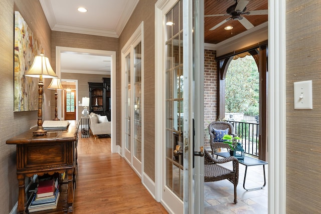 hallway with plenty of natural light, crown molding, light hardwood / wood-style flooring, and french doors