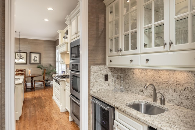 kitchen with light stone countertops, decorative light fixtures, wine cooler, sink, and ornamental molding