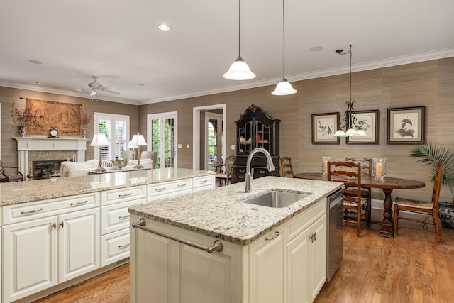 kitchen featuring decorative light fixtures, sink, light stone counters, and a center island with sink