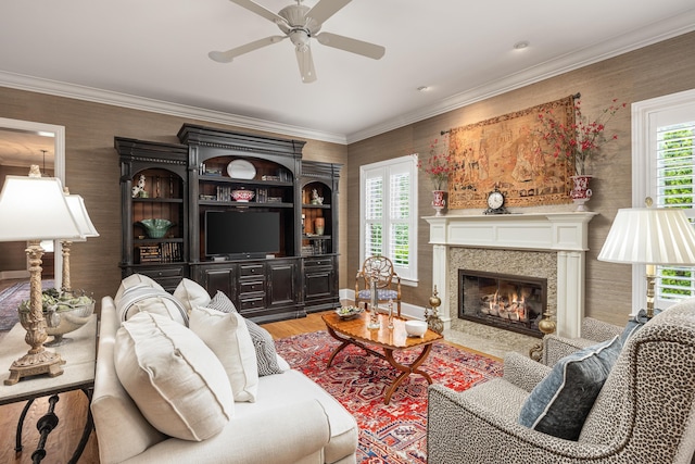 living room with ceiling fan, a premium fireplace, crown molding, and hardwood / wood-style flooring