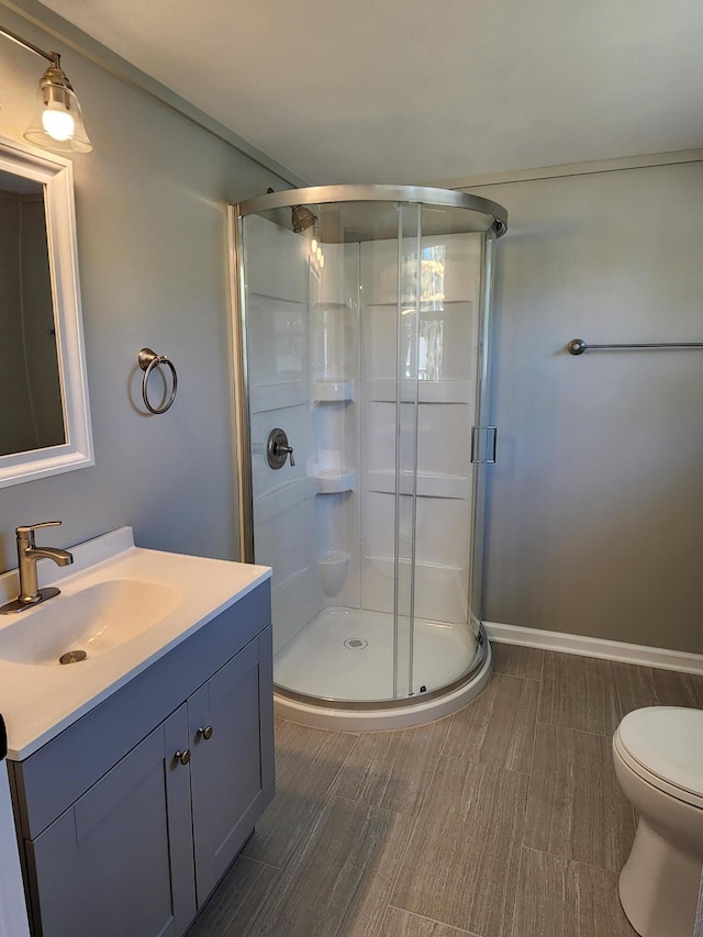 bathroom featuring a shower with door, vanity, hardwood / wood-style floors, and toilet