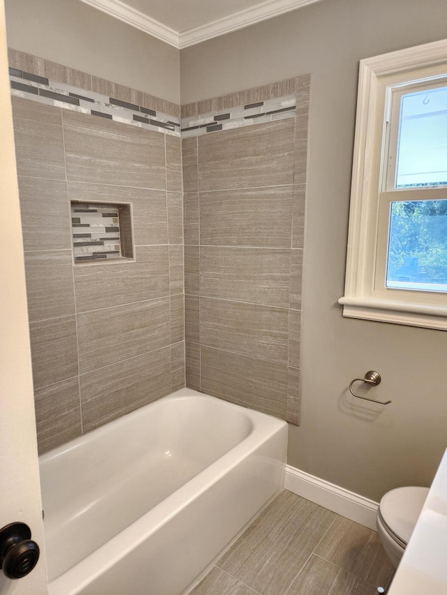 bathroom featuring toilet, crown molding, and tiled shower / bath