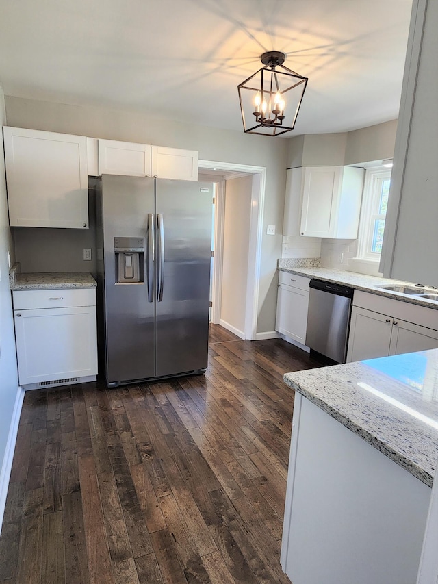 kitchen featuring white cabinets, stainless steel appliances, dark wood-type flooring, and decorative light fixtures