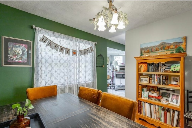 dining room with hardwood / wood-style flooring, a textured ceiling, and an inviting chandelier