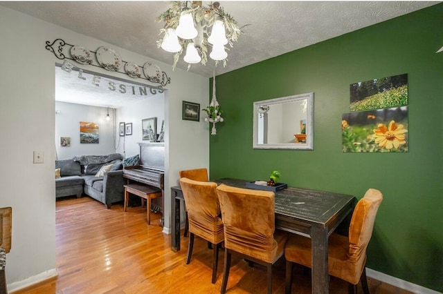 dining area with hardwood / wood-style floors, a chandelier, and a textured ceiling