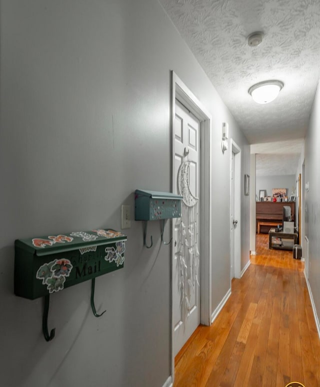 corridor with a textured ceiling and light wood-type flooring