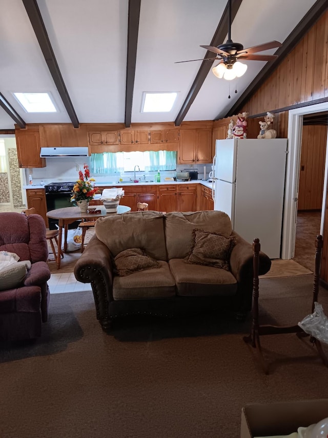 living room featuring a healthy amount of sunlight, wood walls, ceiling fan, and beam ceiling