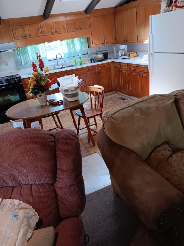 kitchen with black electric range, beam ceiling, sink, and white refrigerator