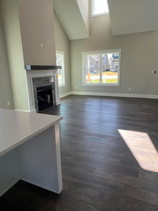 unfurnished living room featuring high vaulted ceiling, a tile fireplace, and dark hardwood / wood-style flooring