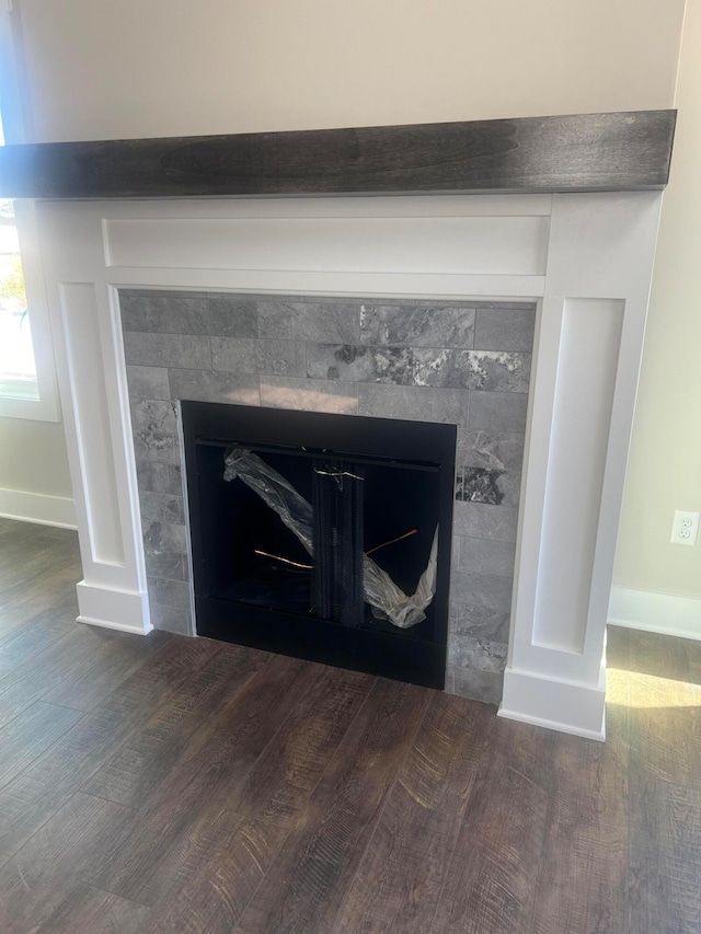 interior details featuring a tiled fireplace and wood-type flooring