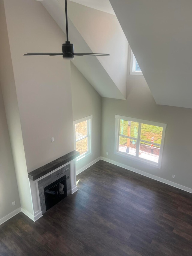 unfurnished living room featuring ceiling fan, high vaulted ceiling, a healthy amount of sunlight, and dark hardwood / wood-style flooring