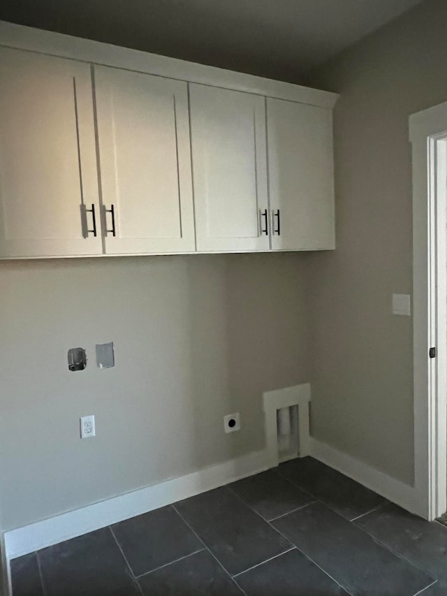 laundry room featuring cabinets, hookup for an electric dryer, and dark tile patterned flooring