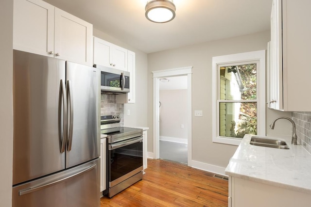 719 Federal St, Chattanooga, TN 37405 - kitchen with light wood finished floors, a sink, stainless steel appliances, decorative backsplash, and white cabinets