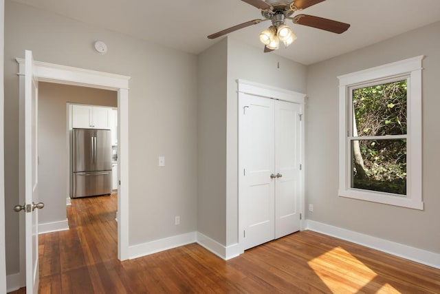 unfurnished bedroom featuring a closet, stainless steel fridge, ceiling fan, and dark hardwood / wood-style flooring