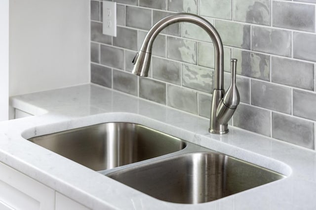 interior details featuring decorative backsplash, sink, and white cabinets