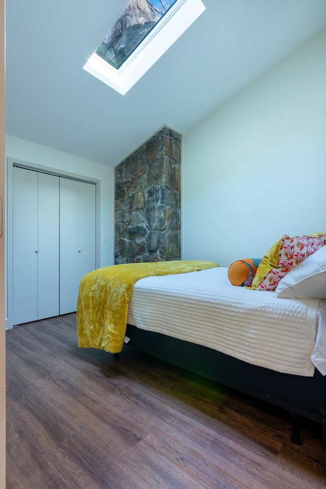 bedroom with a closet, lofted ceiling with skylight, and wood-type flooring