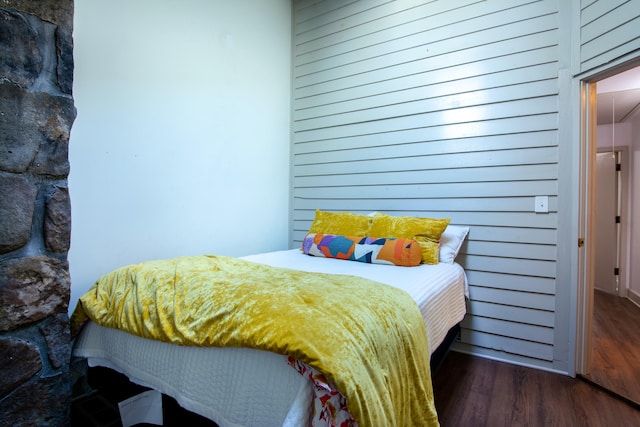 bedroom with wooden walls and dark hardwood / wood-style flooring