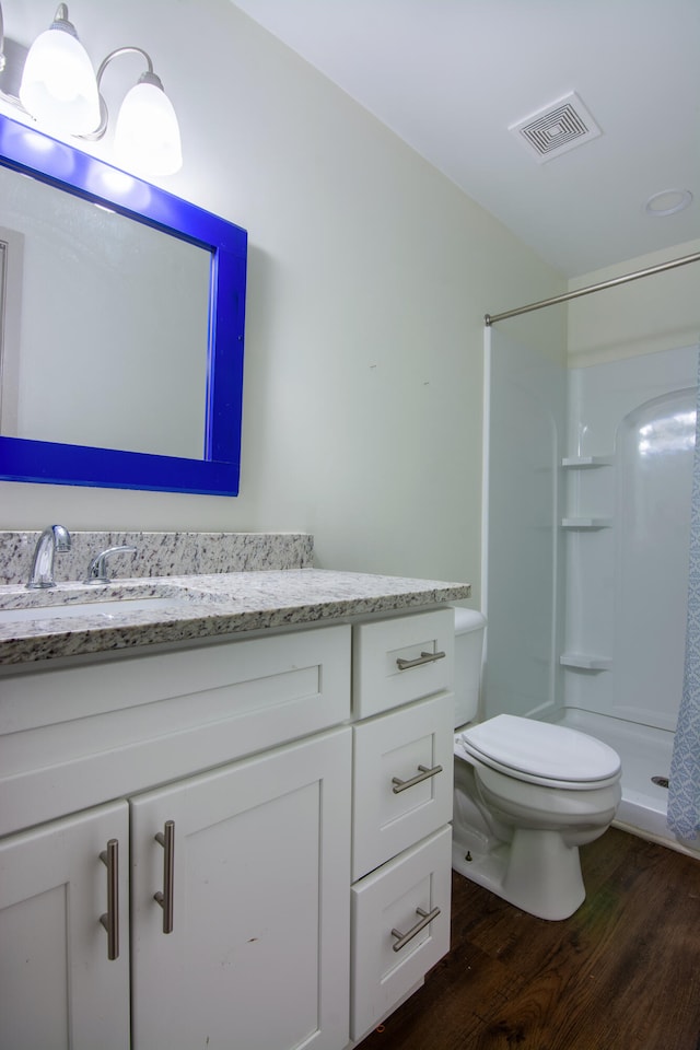 bathroom featuring vanity, hardwood / wood-style floors, a shower, and toilet