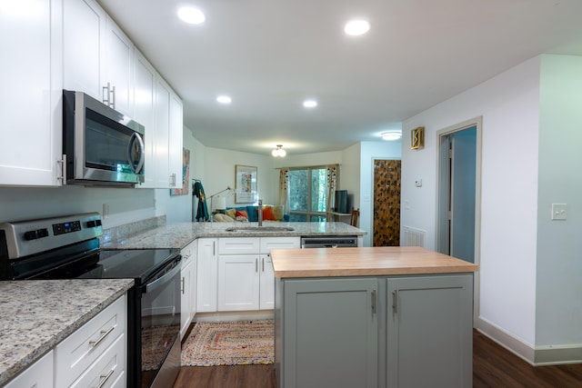 kitchen featuring a kitchen island, dark hardwood / wood-style floors, kitchen peninsula, white cabinets, and appliances with stainless steel finishes