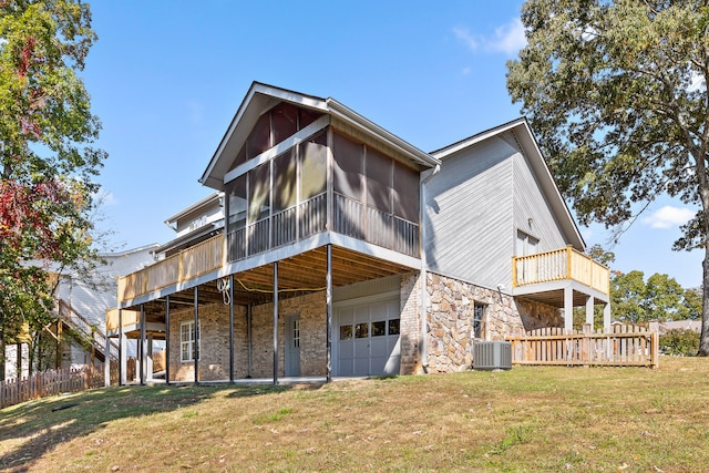 back of property with central AC, a yard, a garage, and a sunroom