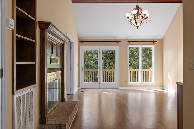 interior space with a notable chandelier, wood-type flooring, and vaulted ceiling