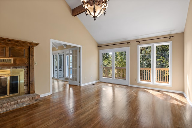 unfurnished living room featuring a brick fireplace, hardwood / wood-style floors, beam ceiling, high vaulted ceiling, and an inviting chandelier