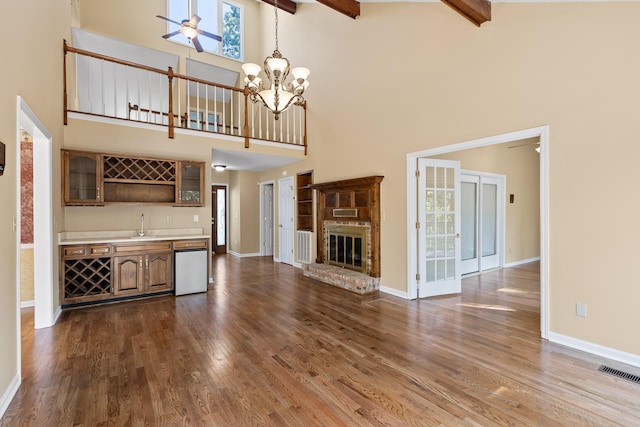 unfurnished living room featuring high vaulted ceiling, beamed ceiling, and hardwood / wood-style floors