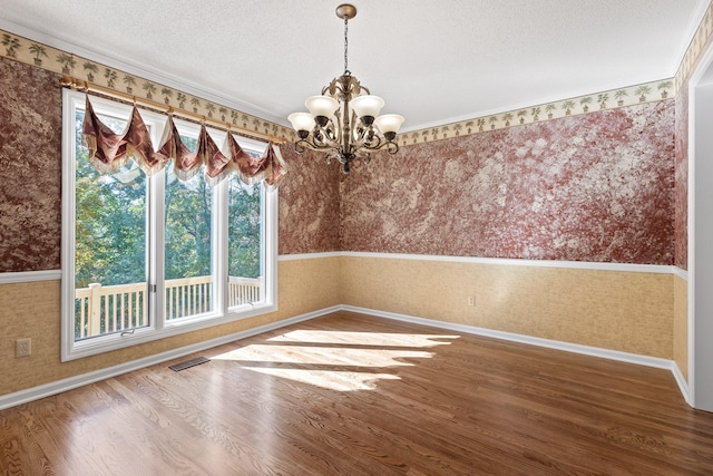 unfurnished dining area with an inviting chandelier, hardwood / wood-style floors, and a textured ceiling