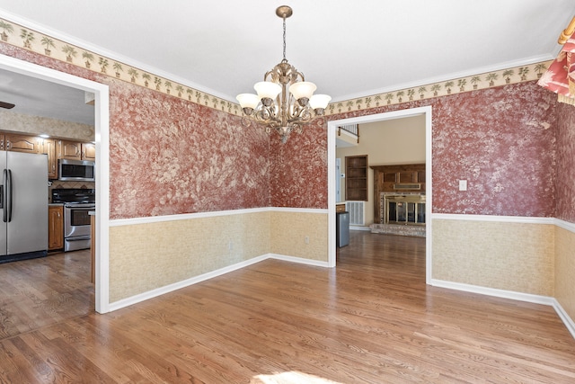 unfurnished dining area featuring light hardwood / wood-style floors, crown molding, and a chandelier