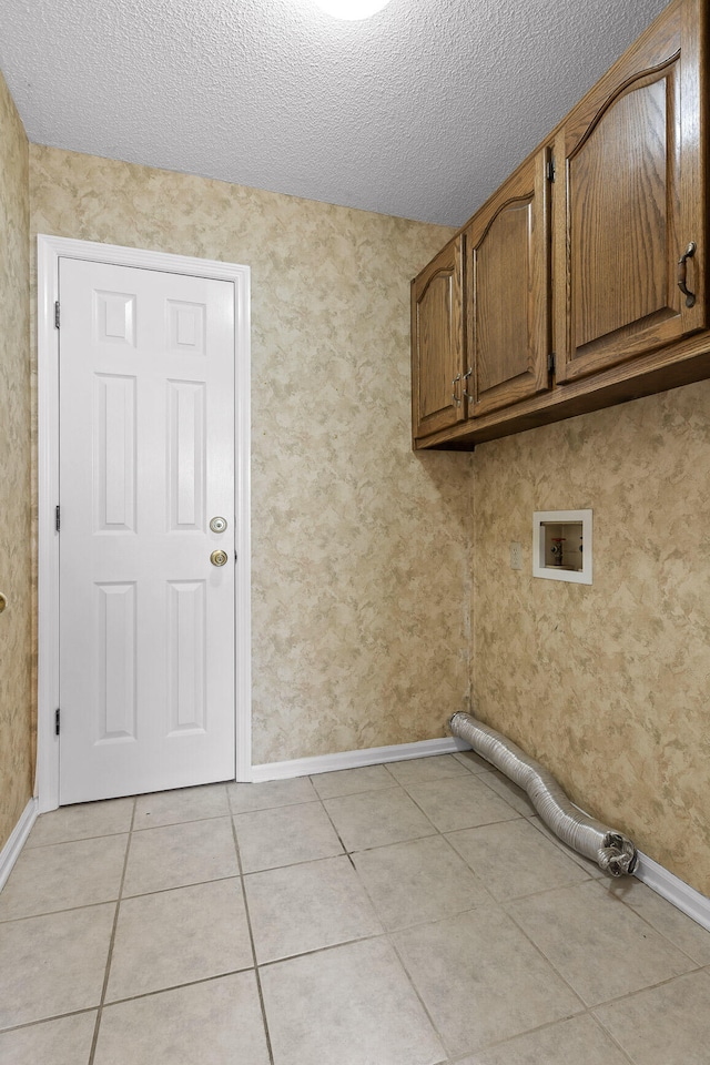 washroom with cabinets, hookup for a washing machine, a textured ceiling, and light tile patterned floors