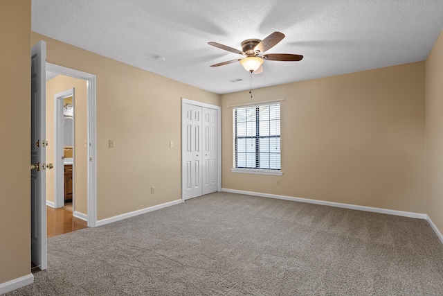 unfurnished bedroom featuring light carpet, a textured ceiling, and ceiling fan