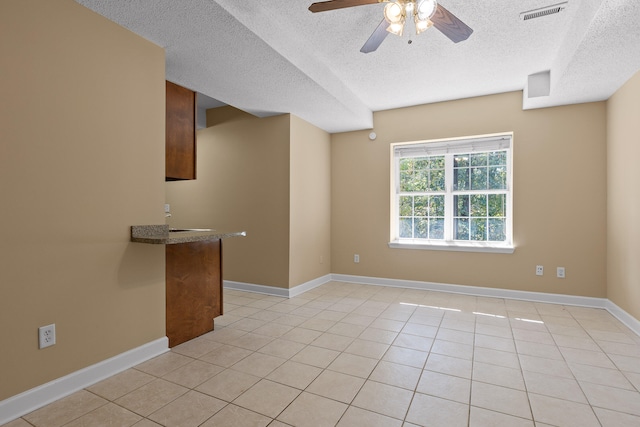 tiled spare room with a textured ceiling and ceiling fan