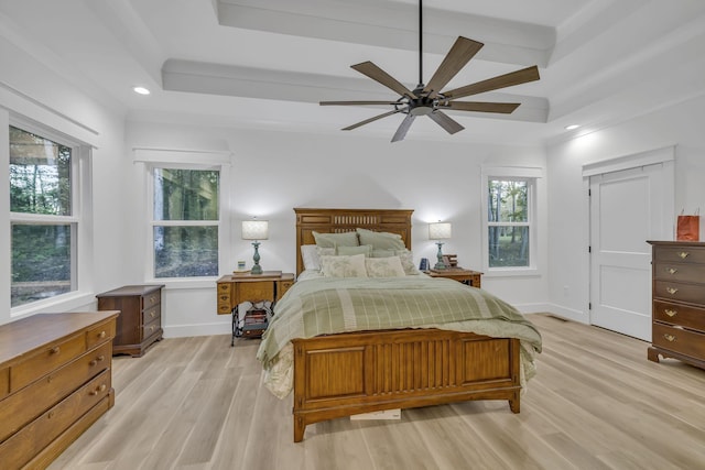 bedroom with beamed ceiling, a tray ceiling, light wood-type flooring, and ceiling fan