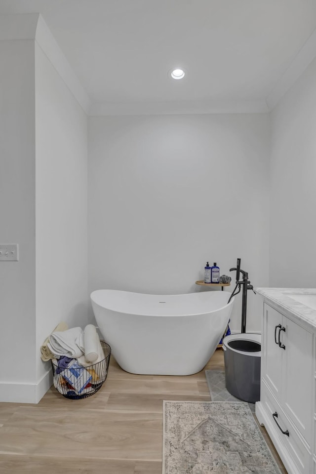 bathroom with vanity, crown molding, wood-type flooring, and a tub