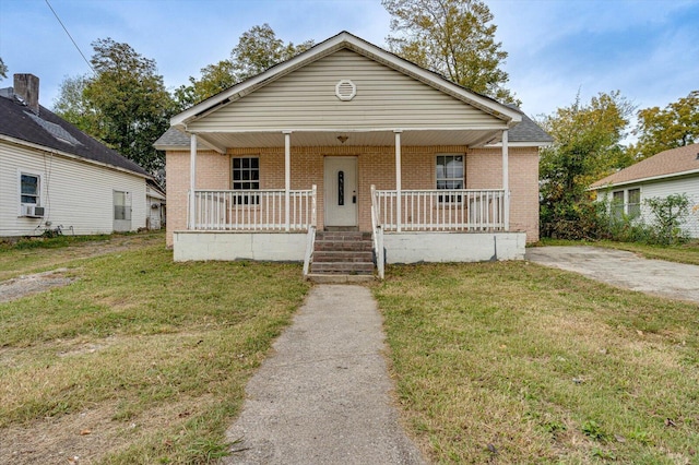 bungalow-style house with covered porch, a front yard, and cooling unit