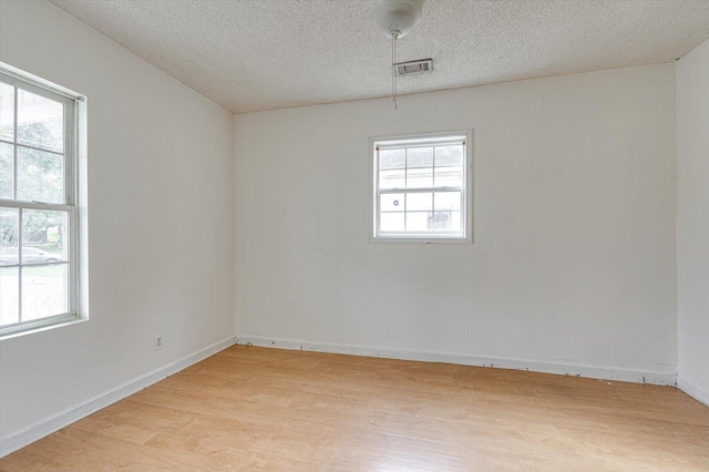 spare room featuring a textured ceiling and light wood-type flooring