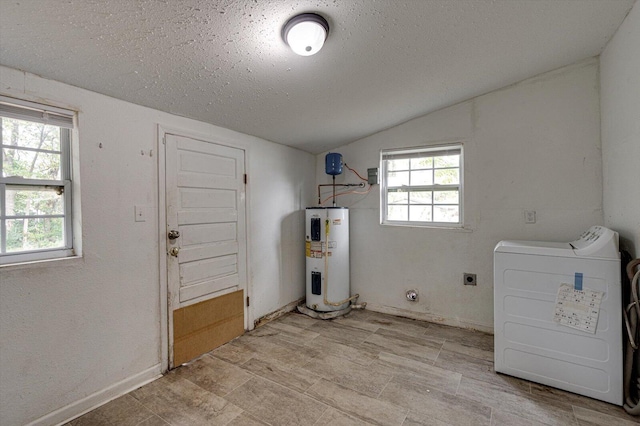 clothes washing area with electric water heater, a textured ceiling, and washing machine and clothes dryer