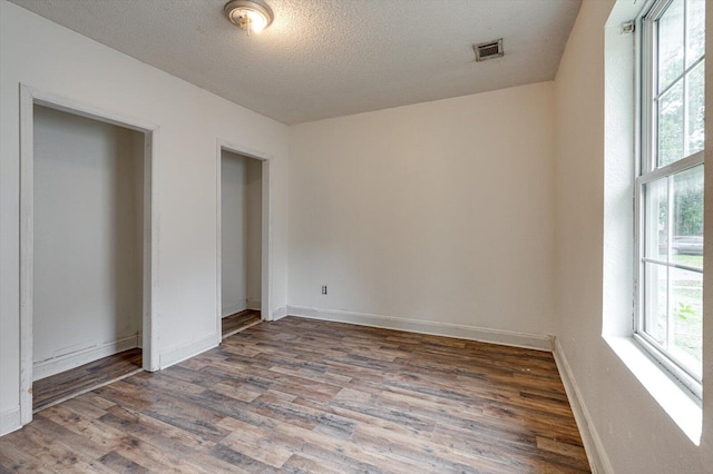 unfurnished bedroom featuring a textured ceiling and dark hardwood / wood-style flooring