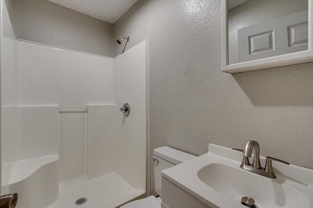 bathroom featuring toilet, a textured ceiling, walk in shower, and vanity