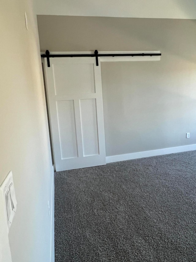 unfurnished room featuring carpet and a barn door