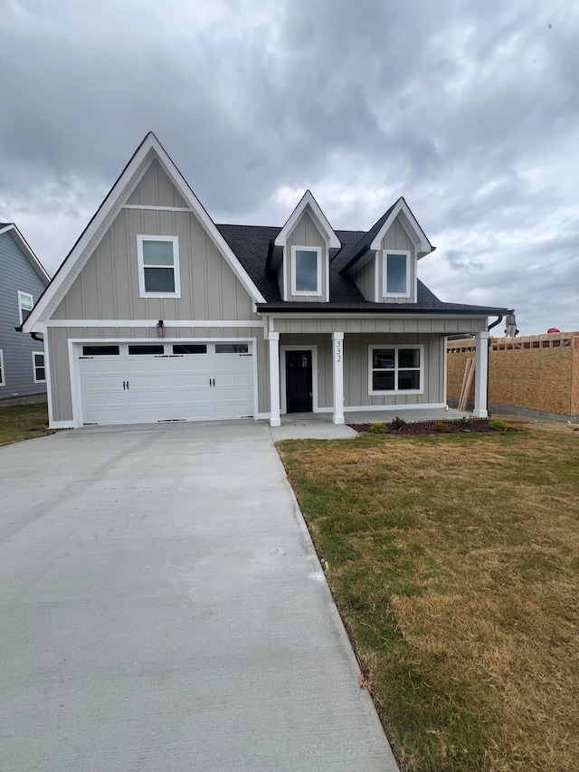 view of front facade featuring a porch, a front lawn, and a garage