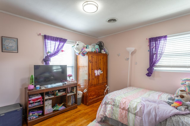 bedroom with ornamental molding and light wood-type flooring