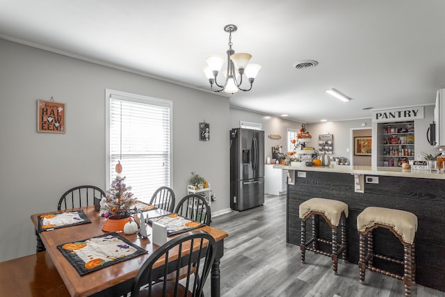 dining room featuring a notable chandelier, wood-type flooring, and ornamental molding