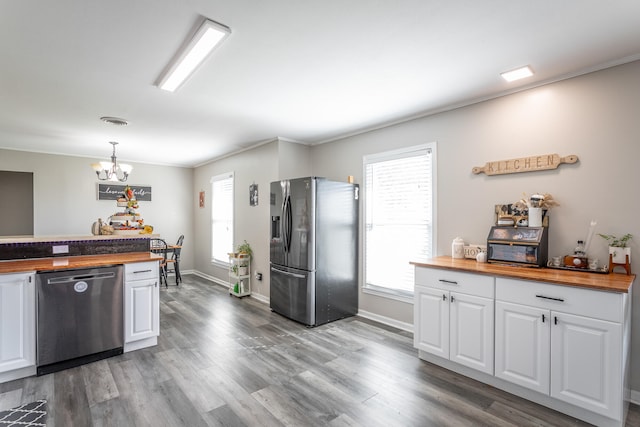 kitchen featuring butcher block countertops, hanging light fixtures, hardwood / wood-style floors, white cabinetry, and appliances with stainless steel finishes