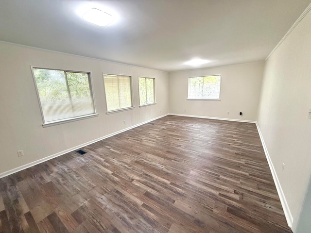 empty room with ornamental molding and dark hardwood / wood-style flooring