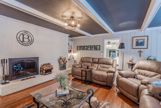 living room featuring crown molding, ceiling fan, light wood-type flooring, and a brick fireplace