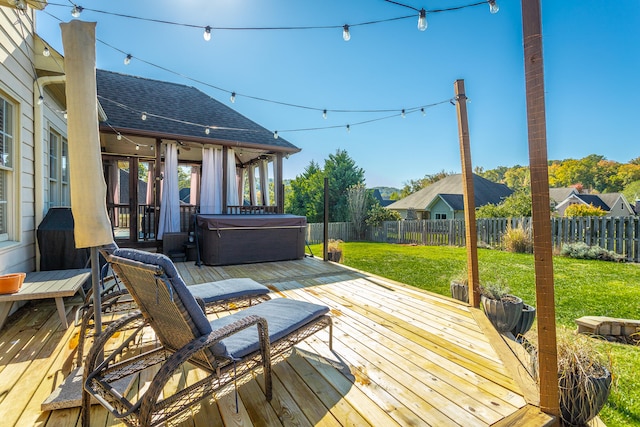 wooden terrace with a hot tub and a lawn