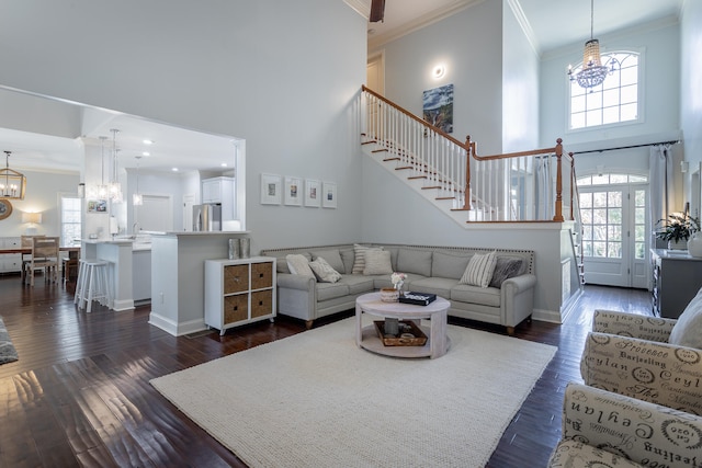 living room with a towering ceiling, a healthy amount of sunlight, and dark hardwood / wood-style floors