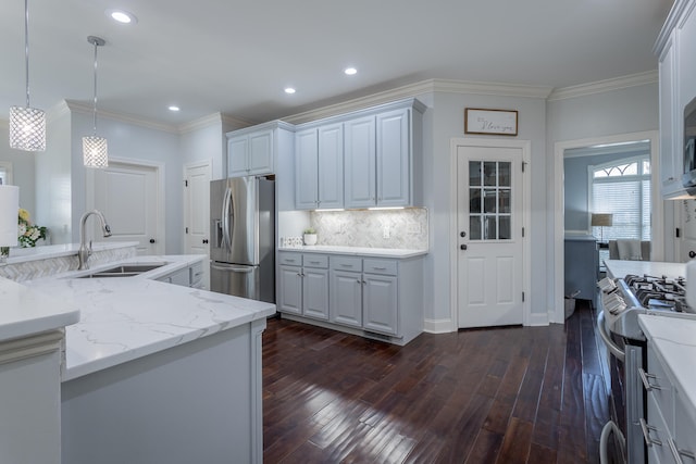 kitchen with appliances with stainless steel finishes, sink, decorative light fixtures, and dark hardwood / wood-style flooring