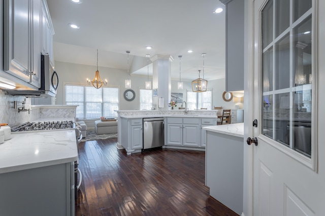 kitchen featuring hanging light fixtures, a kitchen island, dark wood-type flooring, and appliances with stainless steel finishes